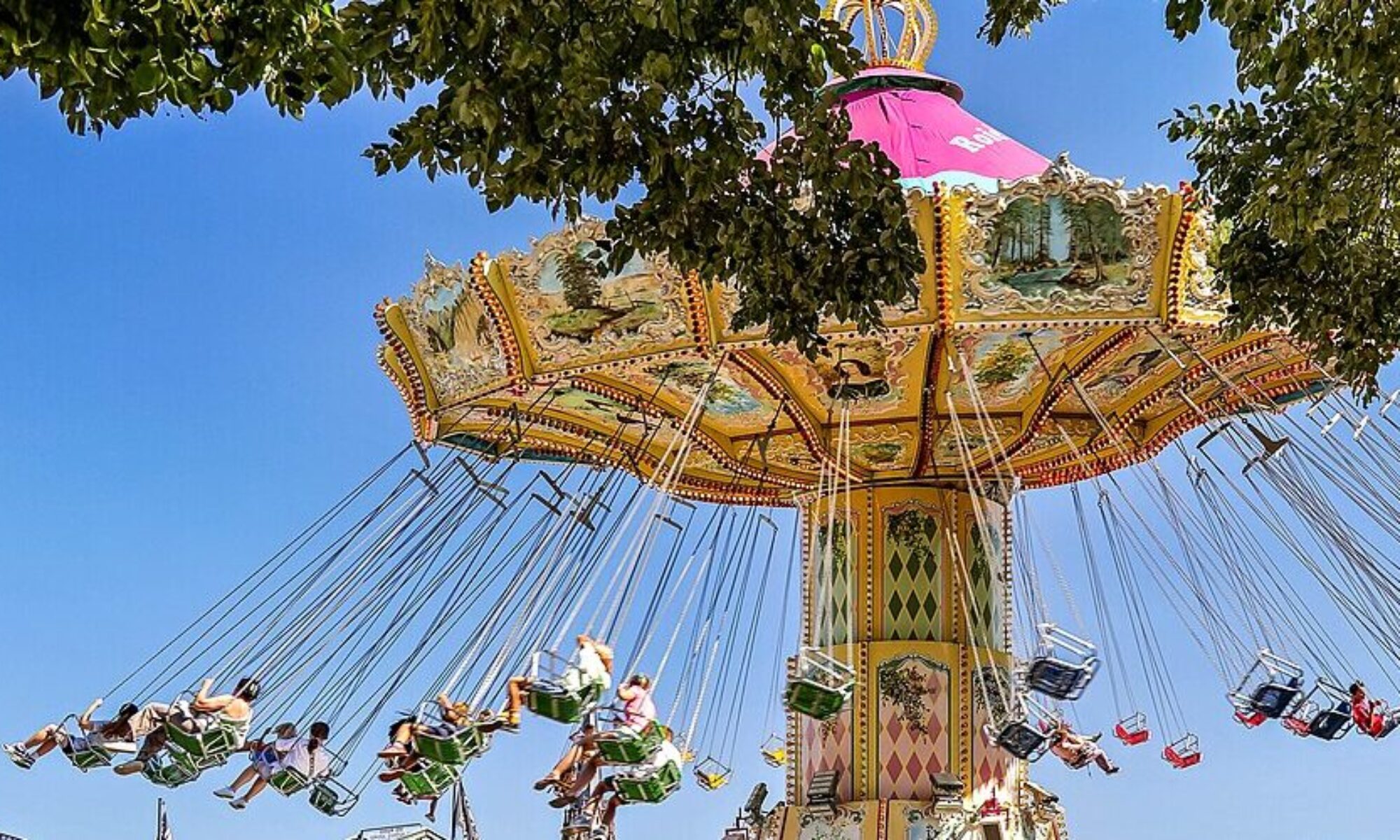 photo showing people on an amusement park ride where they sit on hanging seats and are spun around.